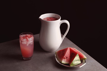 Homemade refreshing drink in glass and plate with watermelon slices on table