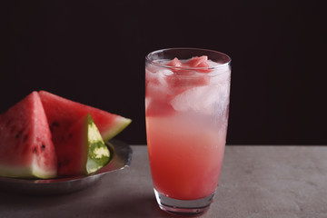 Homemade refreshing drink in glass and plate with watermelon slices on table