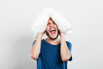 Angry man closing ears with pillow