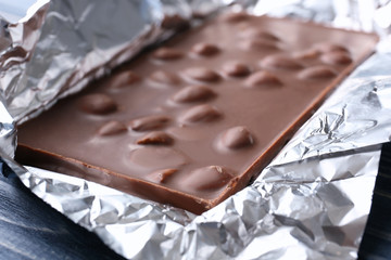 Chocolate bar with nuts in foil, close up