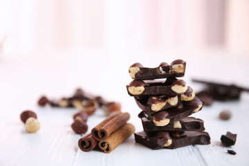 Broken chocolate pieces with nuts and cinnamon on table