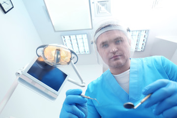 Dentist with mirror and periodontal explorer in clinic