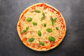 Delicious pizza with melted cheese and basil on grey background