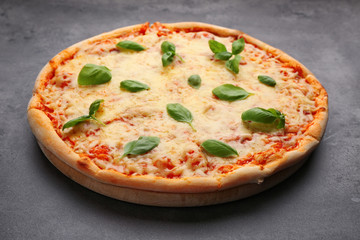 Delicious pizza with melted cheese and basil on grey background