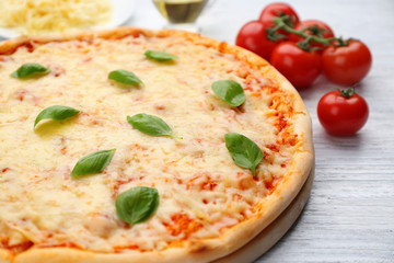 Delicious pizza with melted cheese and basil on wooden table