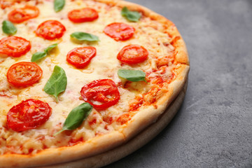 Delicious pizza with tomatoes, basil and melted cheese on grey background