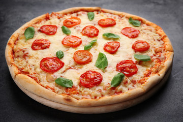 Delicious pizza with tomatoes, basil and melted cheese on grey background