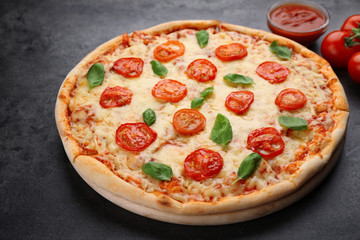 Delicious pizza with tomatoes, basil and melted cheese on grey background