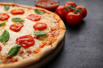 Delicious pizza with tomatoes, basil and melted cheese on grey background
