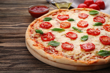 Delicious pizza with tomatoes, basil and melted cheese on wooden background