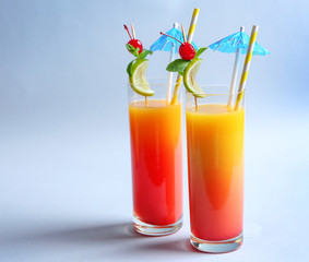 Glasses of Tequila Sunrise cocktail on light background