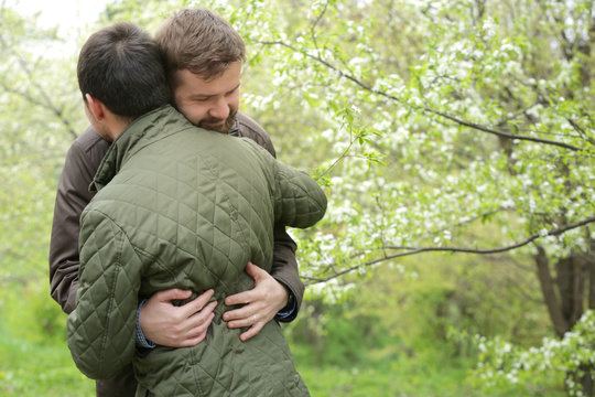 Happy gay couple hugging in park