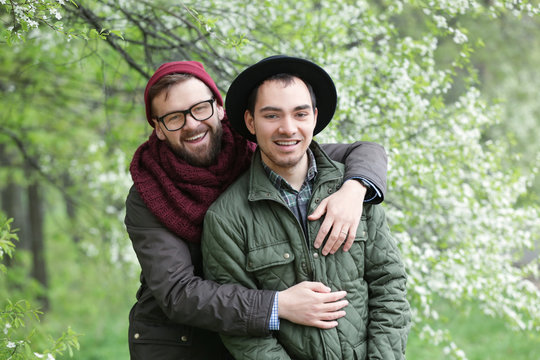 Happy gay couple posing on blurred spring background