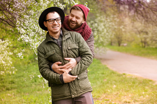 Happy gay couple hugging in park
