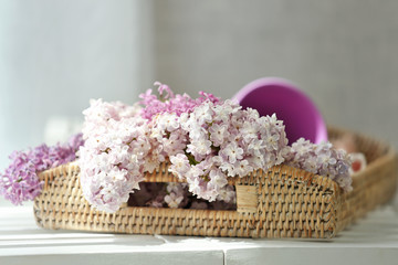 Obraz na płótnie Canvas Wicker tray with beautiful lilac flowers on table