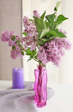 Glass vase with beautiful lilac flowers on wooden table
