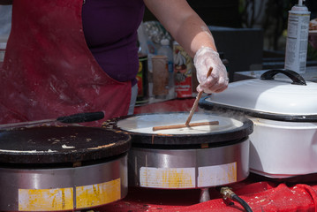 Preparing Crepe Batter onto a grill at an outdoor food festival