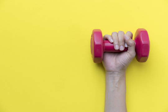woman hand holding red dumbbell on yellow background