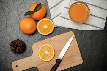 Fresh orange juice in glass dark stone background with kitchen utensils.