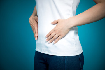 Young woman hand holding her stomach on a blue background