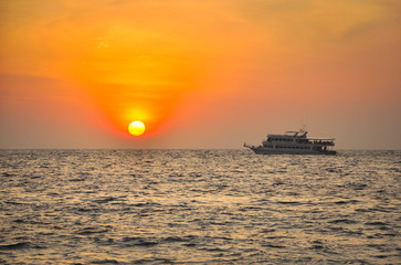 Fototapeta na wymiar Silhouette of sailing ship on the sea near sunset on the sea with beautiful gold sky background, sun goes under horizon of Thailand