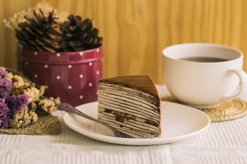 Homemade chocolate crepe cake on white plate and napkin,cover cake by whipped cream,dark chocolate sauce topping,mint and lovely strawberry,tasty dessert for coffee break or tea time,fresh for summer.