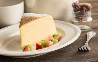 Homemade Japanese cheesecake so delicious, fluffy,lite and soft sparkling with  icing, fresh fruit:kiwi and strawberry. Soft cheesecake Japanese style. Souffle cotton cheesecake put on rustic wood.