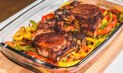 Delicious appetizing pork steaks with vegetables in a glass pan
