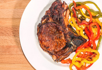 Delicious appetizing steak with vegetables on a plate on a wooden board, free, copyspace