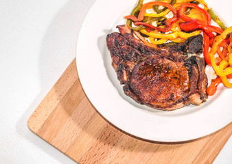 Delicious appetizing steak with vegetables on a plate on a wooden board, free, copyspace