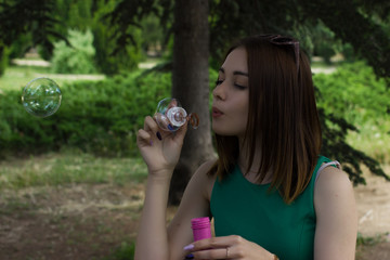Fototapeta premium Young pretty girl blows bubbles, outdoor 