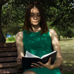 Obraz premium Young pretty girl reads a book, outdoor 