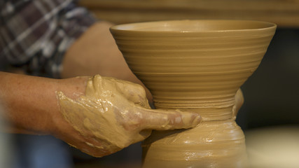 A close-up shot of a craftsman's hand crafting a pottery.