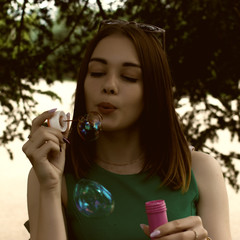 Young pretty girl blows bubbles, outdoor  