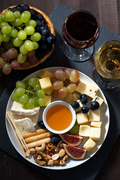 Plate with deli snacks and glasses of wine, top view