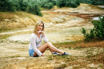Beautiful young woman sitting on the ground . The concept of Hiking during the summer