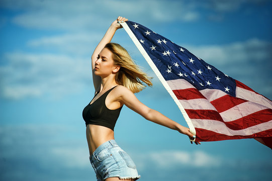 Girl with waving U.S. flag on blue sky background .