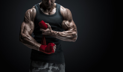 Strong man wrap hands on black background Man is wrapping hands with red boxing wraps isolated on...
