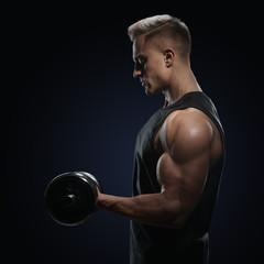 Fototapeta na wymiar Athletic man in training pumping up muscles with dumbbell