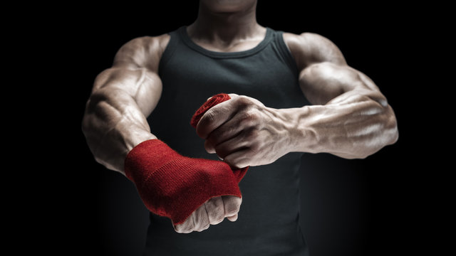 Close-up photo of strong man wrap hands on black background Man is wrapping hands with red boxing wraps isolated on black background Strong hands and fist, ready for training and active exercise