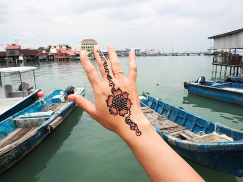 A hand holding in sky for show Henna painting with the boat and sea background in port of Penang, Malaysia.