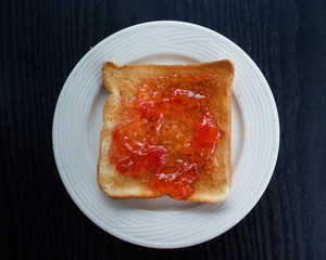 Toast with strawberry jam on black table background . Top view , breakfast
