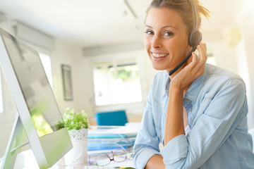 Customer service operator talking on phone in office