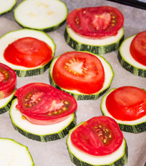  Vegetables prepared for roasting. Sliced tomatoes stacked on slices of zucchini. Selective focus.