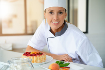 Portrait of pastry chef standing by raspberry cake
