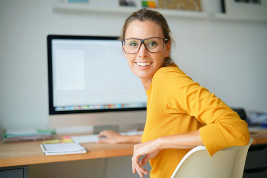 Cheerful trendy girl working on desktop computer