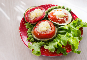 Appetizer of zucchini and tomatoes, baked with cheese on lettuce leaves with green peas. Close-up. Selective focus.