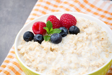 Oatmeal porridge in bowl with berries raspberries and blackberries.