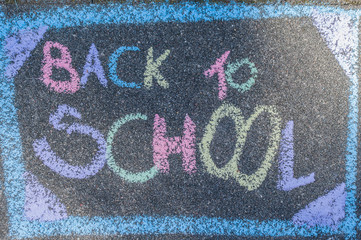 Back to school concept, written with colorful chalks on asphalt