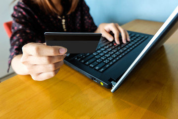 Young woman holding credit card and using laptop, shopping online concept